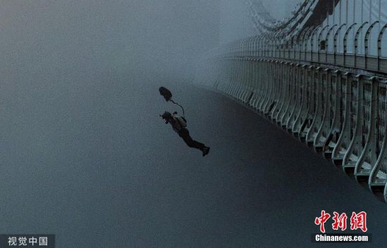 8月29日讯，英国布里斯托尔，摄影师吉姆・兰帕德假日清晨去拍摄雾中的克利夫顿悬索桥，返回途中遇到一位可能准备定点跳伞的男子。他跟随男子返回桥上。尽管有保安阻挠，这名男子还是纵身一跃，跳入了云雾缭绕的埃文峡谷。图片来源：视觉中国