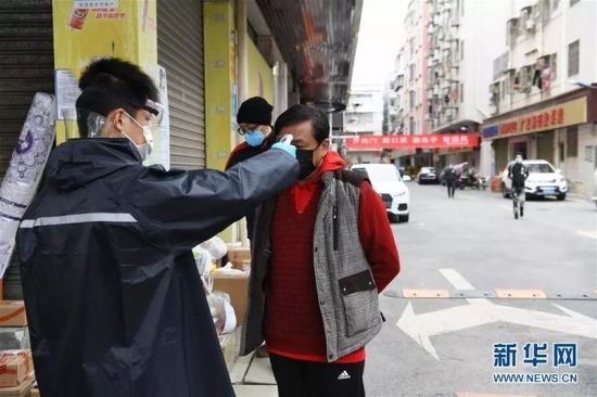 在深圳市宝安区新安街道海乐社区，工作人员为进出的居民测量体温(2月9日摄)。新华社记者梁旭摄