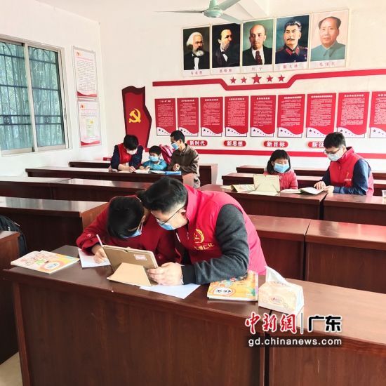 扶贫干部在村委会议室对学生进行辅导。仁化县政府供图。 