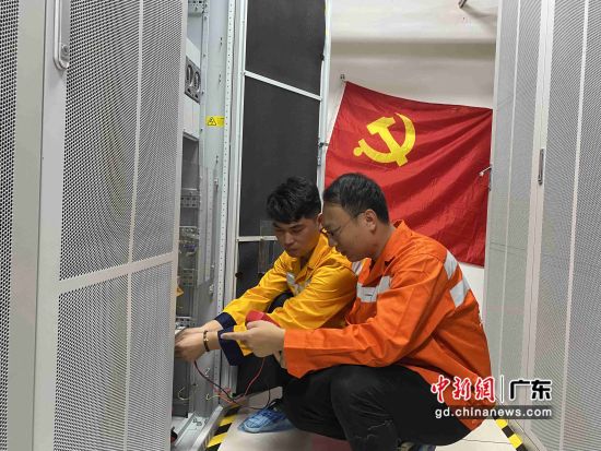 华明裕(右)在机房对通信设备进行检修。 作者 刘成益