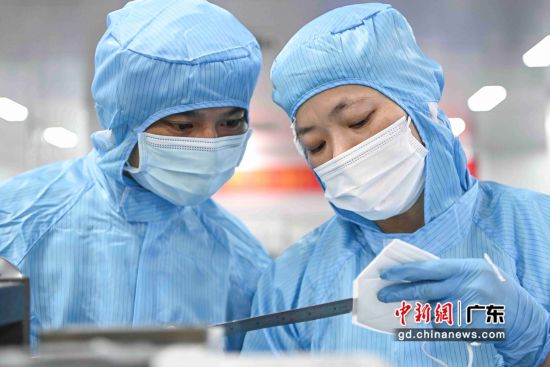 两名金发科技股份有限公司工作人员在立体口罩车间内使用尺子检查KN95防疫口罩质量。 作者 陈骥�F