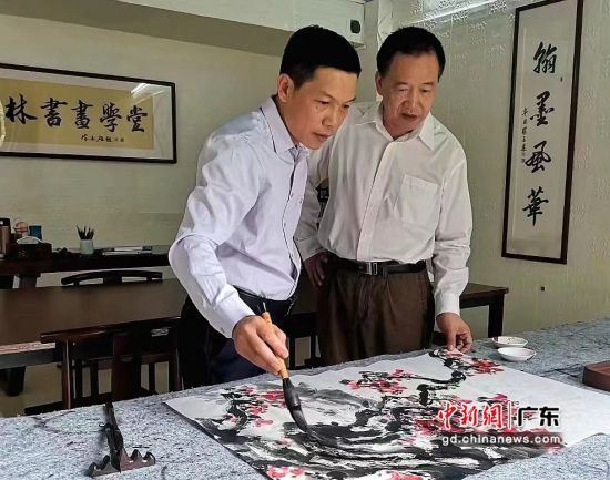 陈志雄(左)在创作国画红棉。受访者 供图