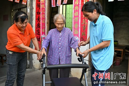 护理员为老人介绍助行器。记者 陈骥�F 摄
